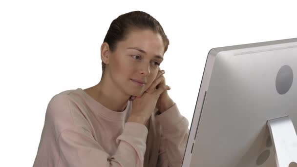 Blonde girl with pink pullover looking at monitor of computer watching video on white background. — Stock Video