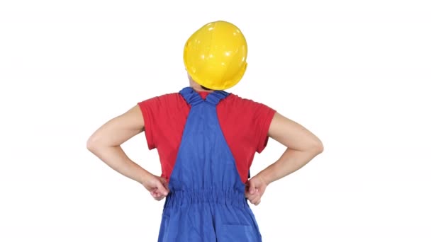 Trabajadora de la construcción con las manos en las caderas mirando algo sobre fondo blanco. — Vídeo de stock