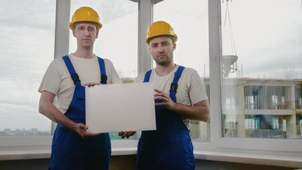 Δύο λυπημένοι χτίστες με φύλλα ή αφίσα που ψάχνουν για δουλειά. — Αρχείο Βίντεο
