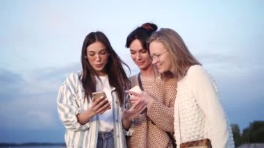 Akıllı telefondan komik bir şey izledikten sonra gülen bir grup kadın arkadaş.