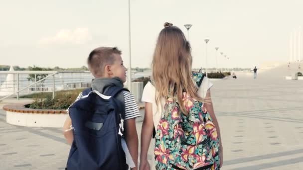 Un niño y una niña caminando con mochilas . — Vídeos de Stock