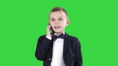 Sevimli küçük çocuk onun akıllı telefon konuşuyor ve Yeşil Ekranda koyu bir takım elbise ayakta, Chroma Key.