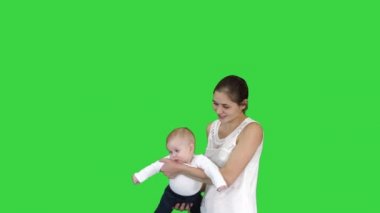 Anne elleri üzerinde bebeğini döndürür Bebek yeşil ekranda annelerin elinde uçan, Chroma Anahtar.