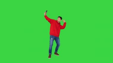 Heyecanlı sıradan adam dans ediyor ve telefonuyla Chroma Key 'de selfie çekiyor..
