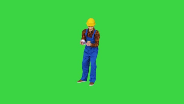 Bauunternehmer, der sein Gehalt zählt und auf einem Green Screen auf komische Weise tanzt, Chroma Key. — Stockvideo