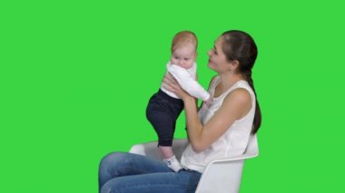 Anne ve sevimli bebek Yeşil Ekran, Chroma Anahtar bir sandalyede oturan.