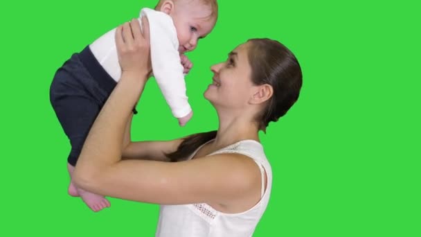 Positiver kleiner netter Junge mit wunderschöner Mutter, die ihr Baby auf einem grünen Bildschirm aufrichtet, Chroma-Schlüssel. — Stockvideo