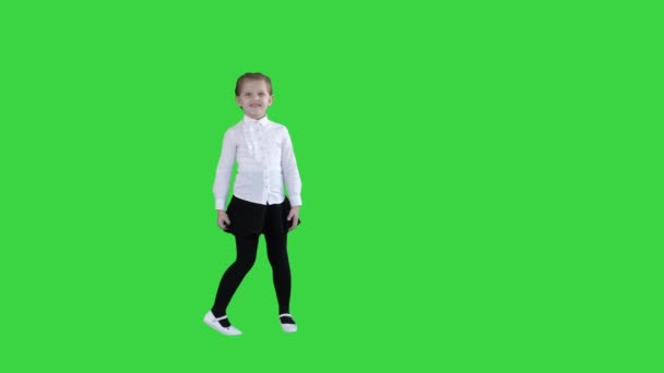 Lycklig söt liten flicka som går i ramen och pratar med kameran på en grön skärm, Chroma nyckel. — Stockvideo