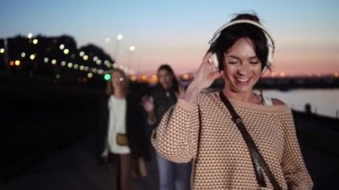 Genç güzel sevimli hipster kadın yürüyüş ve kulaklık müzik dinleme.