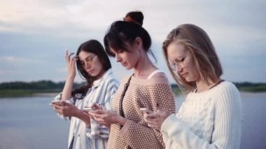 Dostluk, teknoloji ve internet konsepti - akıllı telefonlar ile üç genç kadın açık havada.