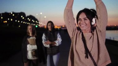 Şık giyinmiş, kulaklıklı, yürüyen ve müzikten hoşlanan bir kadın..