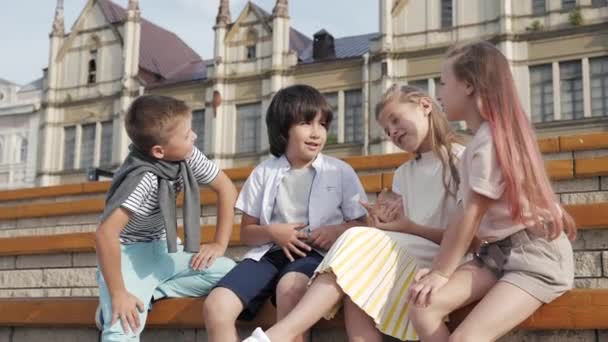 Чотири дитини сидять разом посміхаючись і розмовляючи . — стокове відео