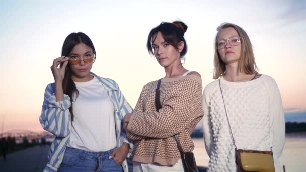 Trois femmes sérieuses regardent la caméra au coucher du soleil . — Video