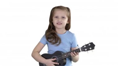 Küçük kız şarkı ve beyaz arka planda kameraya doğru yürürken küçük gitar çalıyor.
