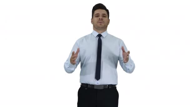 Young businessman walking in frame and talking to camera presenting something on white background. — Stock Video