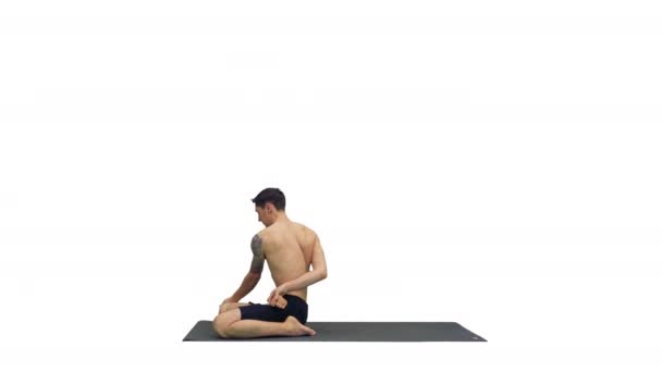 Um jovem homem forte fazendo exercícios de ioga estende as pernas padmasana no fundo branco. — Vídeo de Stock