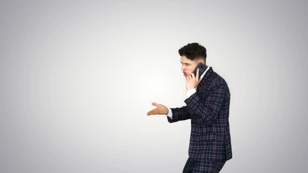 Jeune homme émotionnel en colère en costume formel parlant au téléphone et dansant après sur fond de dégradé. — Video