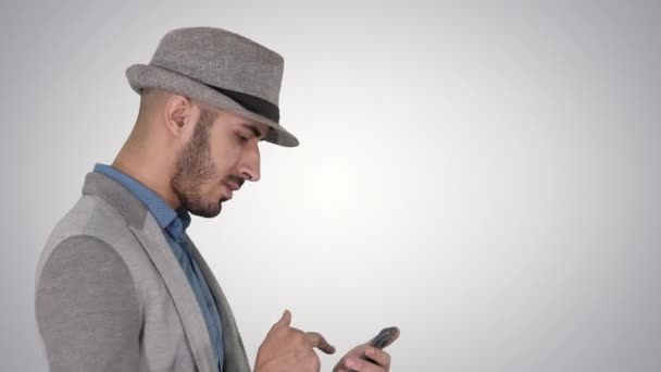 Homme occasionnel arabe sérieux utilisant un smartphone tout en marchant sur fond de dégradé . — Video