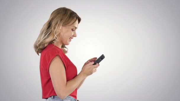 Feliz bonito bela jovem jogar jogos por telefone móvel no fundo gradiente. — Vídeo de Stock