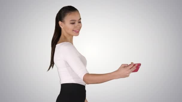 Joven morena tomando foto selfie en smartphone sonriendo alegre y caminando sobre fondo degradado. — Vídeos de Stock