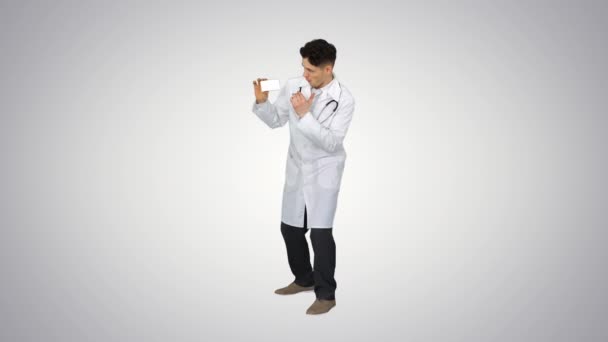 Young doctor presenting new pills and dancing on gradient background. — Stock Video