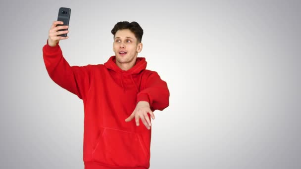 Opgewonden casual man dansen en het maken van selfie met zijn telefoon op gradiënt achtergrond. — Stockvideo