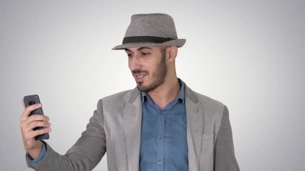 Attraktiv man i casual kläder hatt hipster stylerecording vlog eller göra ett videosamtal på gradient bakgrund. — Stockvideo