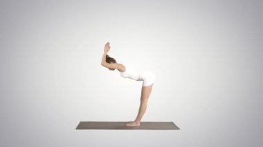 Uttanasana'da ayakta yoga egzersizi yapan güzel model, degrade arka planda ayak bileklerinin arkasında avuç içi ile.