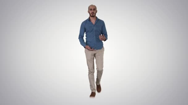Arabo casual uomo a piedi e parlando con fotocamera su gradiente sfondo. — Video Stock