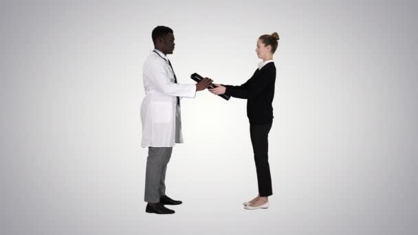 Pacient přijde k doktorovi s rentgenem Fyzioterapeutistou, který vysvětluje rentgen pacienta na pozadí gradientu. — Stock video