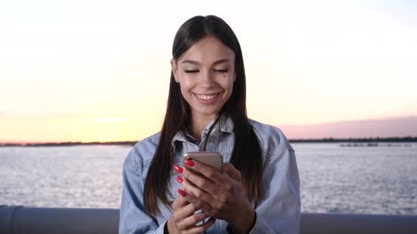 Mladá usměvavá dívka pomocí mobilního telefonu a usmívání. — Stock video
