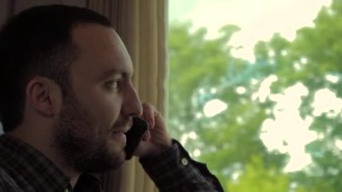 Trende otururken telefonda konuşan çekici bir adam..