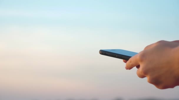 Mujeres mano usando teléfono móvil con un cielo despejado en el fondo . — Vídeos de Stock