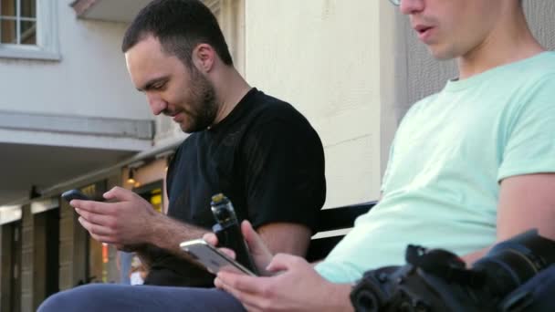 Hombre fumar sigarette electrónica al aire libre cerca de otro chico. — Vídeos de Stock