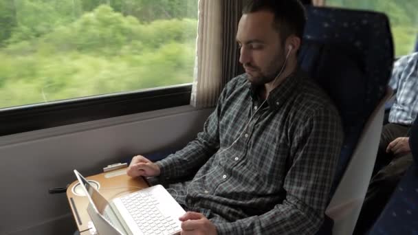 Designer uomo creativo che lavora sul suo computer portatile in un treno. — Video Stock