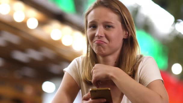 Zklamaná dívka pomocí telefonu v kavárně ve večerních hodinách. — Stock video