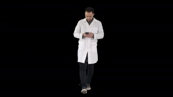 Doctor caminando y escribiendo un mensaje en el teléfono, Alpha Channel — Vídeos de Stock