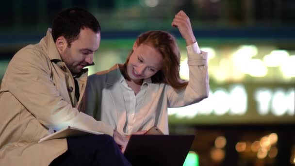 Young co-workers vrouw en man zitten buiten werken op laptop computer. — Stockvideo