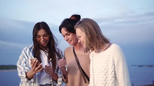 Amis féminins regardant l'écran de téléphone intelligent et riant . — Video