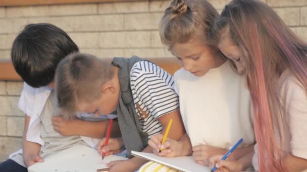 Cuatro niños sentados y pintando al aire libre. — Vídeos de Stock