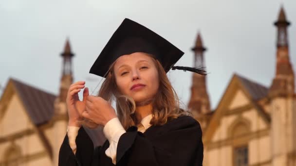 Красивая молодая женщина выпускник выпрямляет волосы и кепку . — стоковое видео