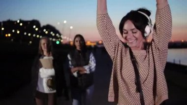 Mutlu genç kadın rıhtımda yürürken gülümseyerek kulaklıkla müzik dinler.