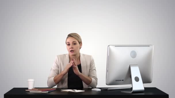 Cute businesswoman looks at the camera in her office and talks on gradient background. — Stock Video