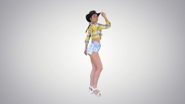 Young cowgirl dancing on gradient background. — Stock Video