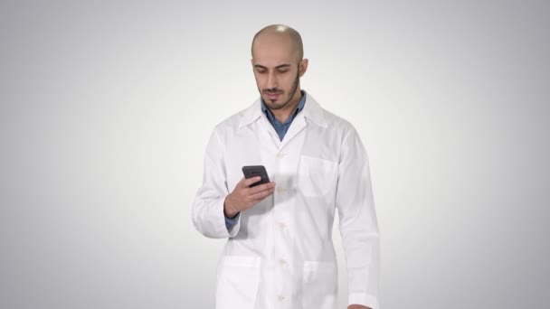 Maschio arabo messaggio di sms medico al telefono mentre si cammina su sfondo gradiente . — Video Stock