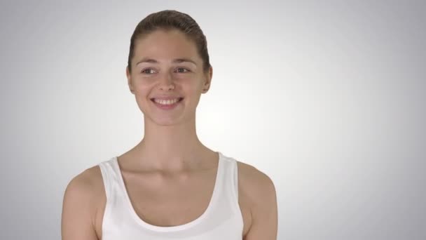 Happy young woman looking at camera with smile while walking on gradient background. — Stock Video