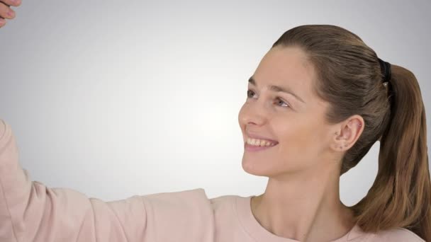 Sonriente mujer de pelo rubio alegre haciendo selfie sobre fondo degradado . — Vídeo de stock