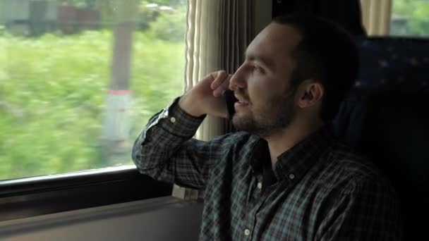 Hezký muž mluví na mobilním telefonu ve vlaku. — Stock video