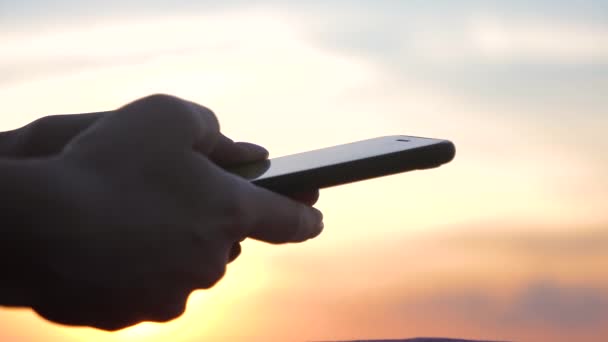 Жінка використовує смартфон на заході сонця. Світло захід сонця, золота година . — стокове відео