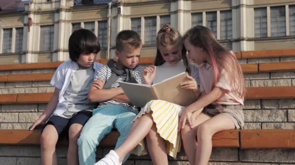 Přátelská skupina dětí čtení knihy venku. — Stock video